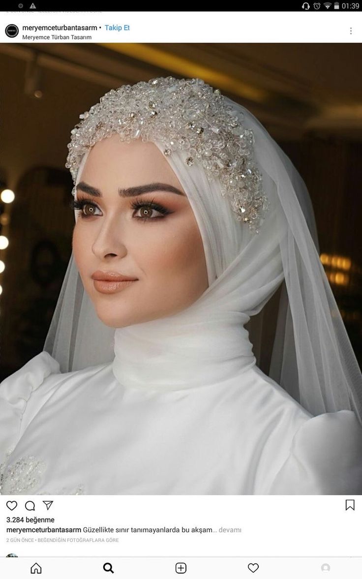 a woman wearing a white veil and headpiece with pearls on her head is looking at the camera