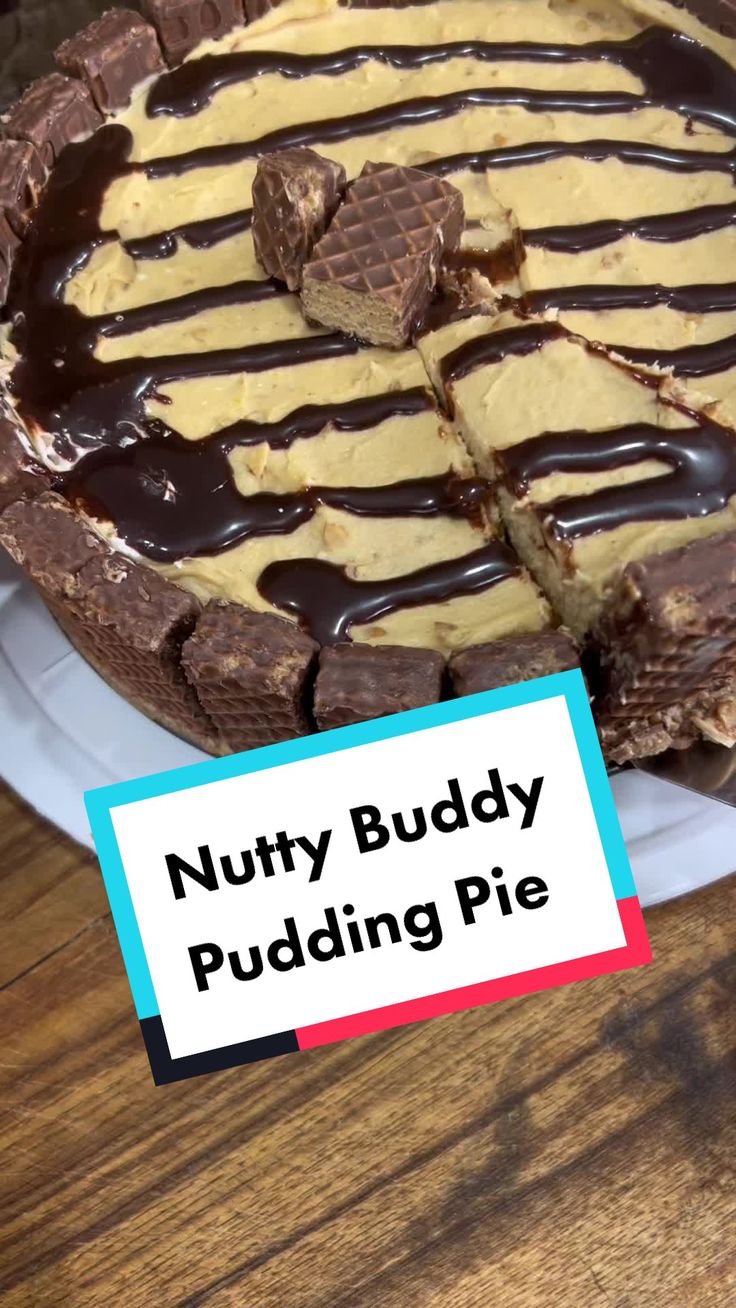 there is a chocolate and peanut butter pie on the table with a sign that says nutty buddy pudding pie