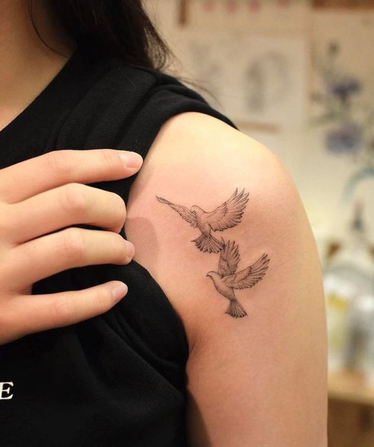 a woman with a tattoo on her arm holding a bird in one hand and a dove in the other