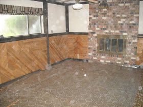 an empty room with wood paneling and a brick fireplace