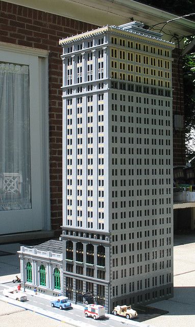 a model of a tall building with cars parked in front of it on the street