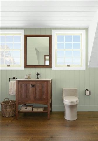 a white toilet sitting next to a wooden sink vanity in a bathroom under a mirror