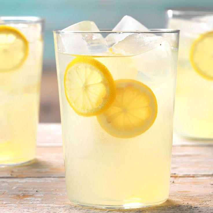 two glasses filled with lemonade on top of a wooden table