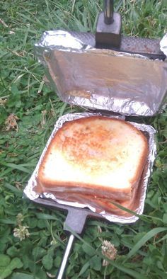 a toasted sandwich sitting on top of a piece of tin foil in the grass