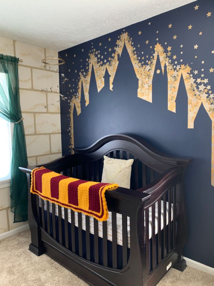 a baby's room decorated in blue and gold with a castle mural on the wall