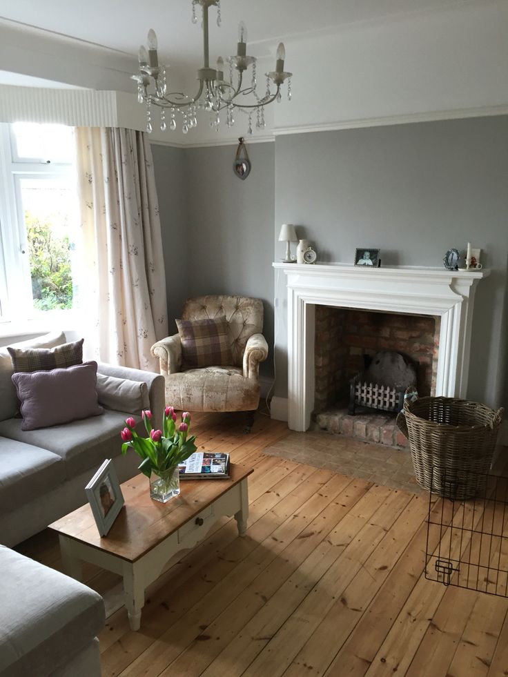 a living room filled with furniture and a fire place under a chandelier in front of a window