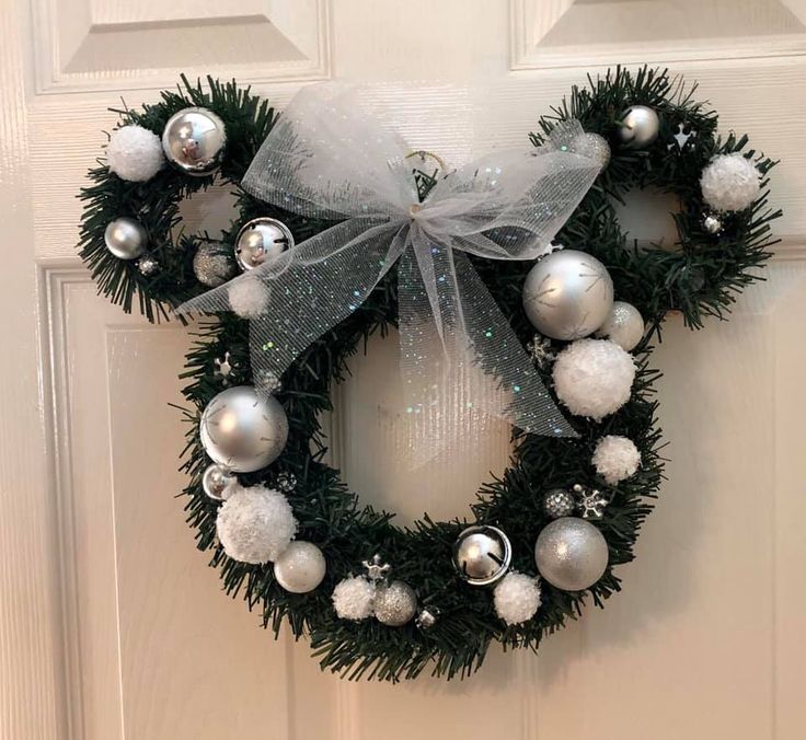 a christmas wreath with silver and white ornaments hanging on the front door to welcome guests