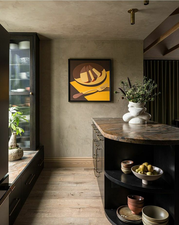 a kitchen with an island in front of a painting on the wall and plates on the counter