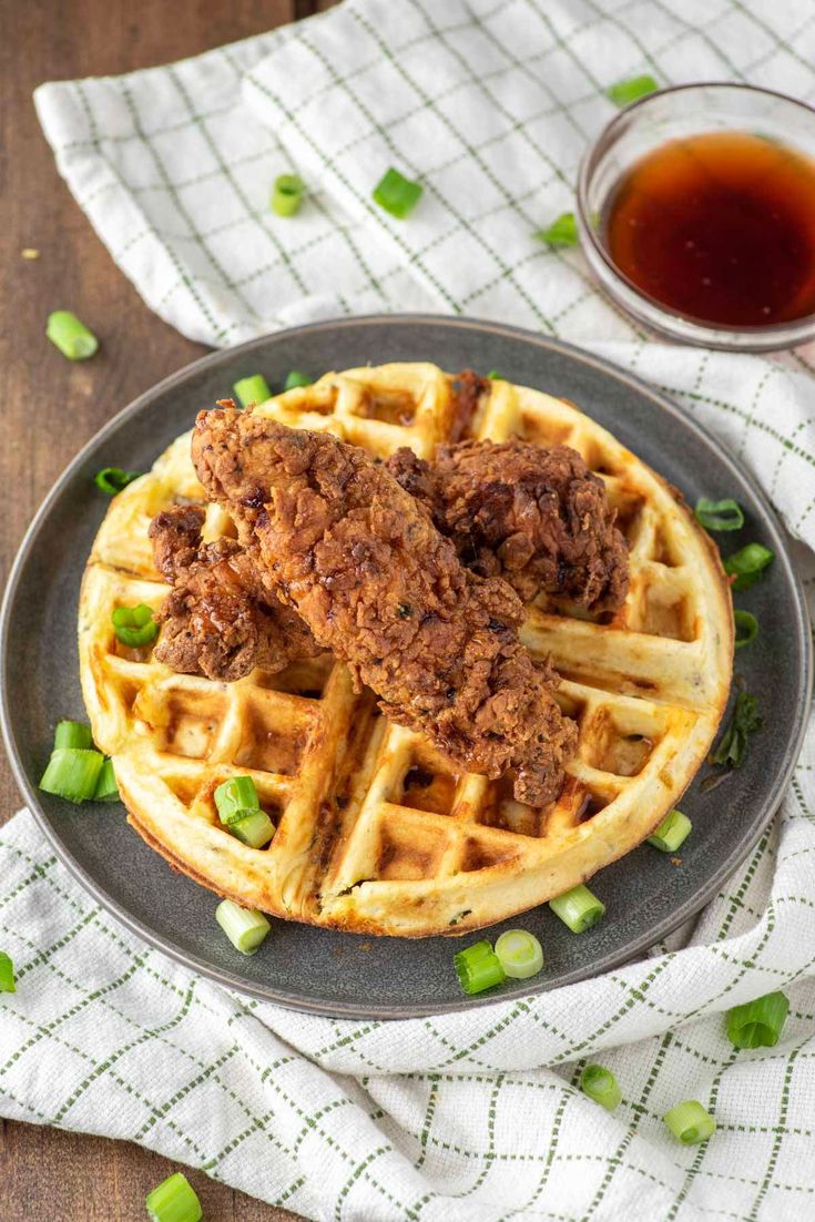 fried chicken and waffles on a black plate with green onions in the background