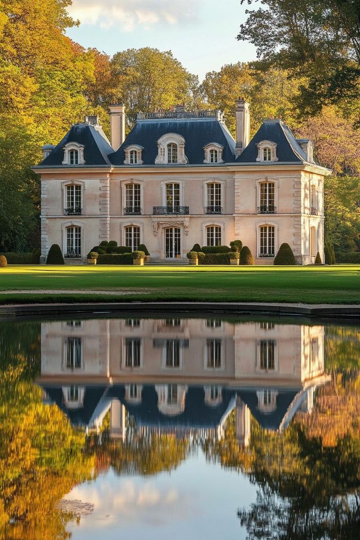 a large house sitting on top of a lush green field next to a body of water