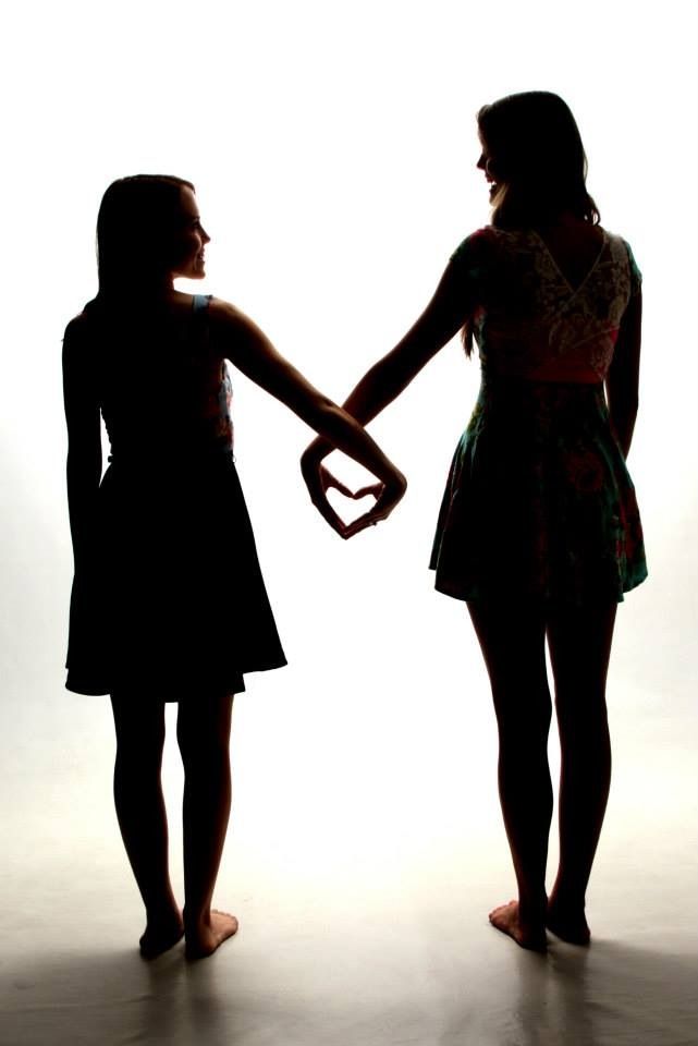 two girls holding hands in silhouette against a white background