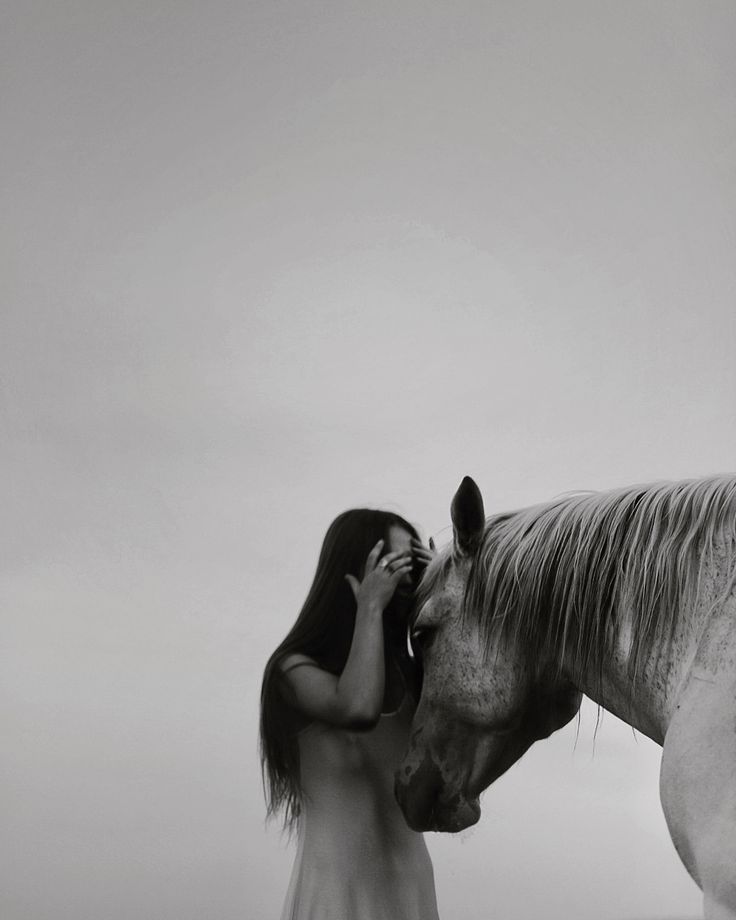 a woman standing next to a white horse