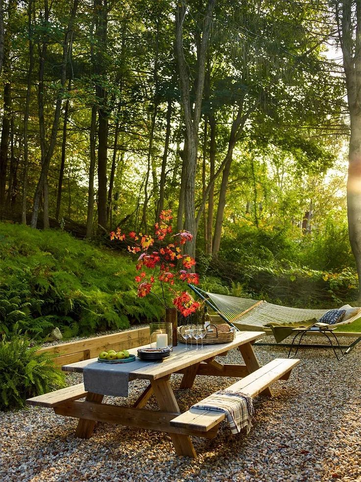 a picnic table and hammock set up in the middle of a wooded area