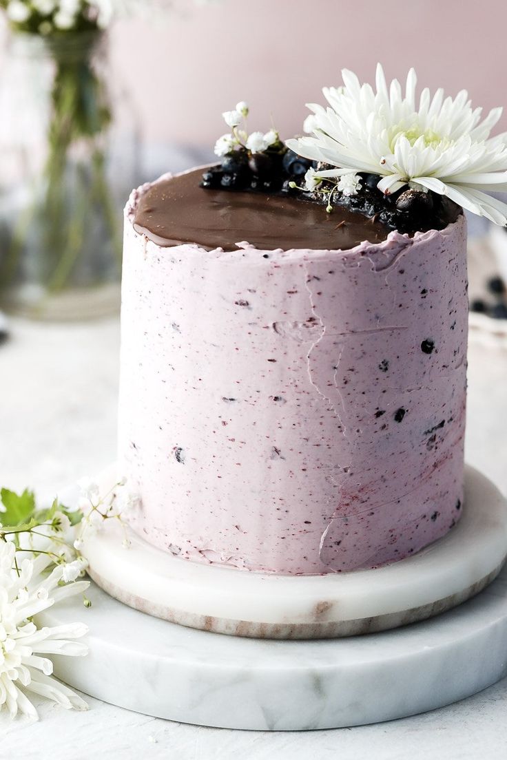 a pink cake with chocolate frosting and white flowers