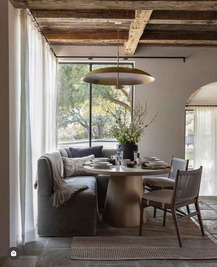 a living room with a couch, table and chairs in front of a large window