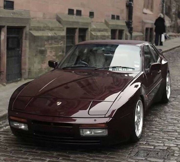 a maroon sports car parked on a cobblestone street