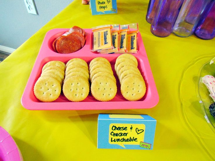 a pink tray filled with crackers and fruit on top of a yellow table cloth