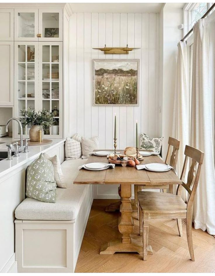 a kitchen with white walls and wood flooring, along with a wooden dining table set for four