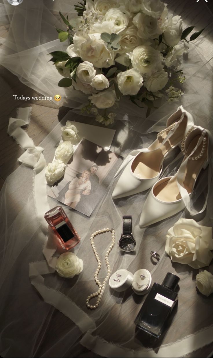 a bouquet of white flowers sitting on top of a table next to shoes and jewelry