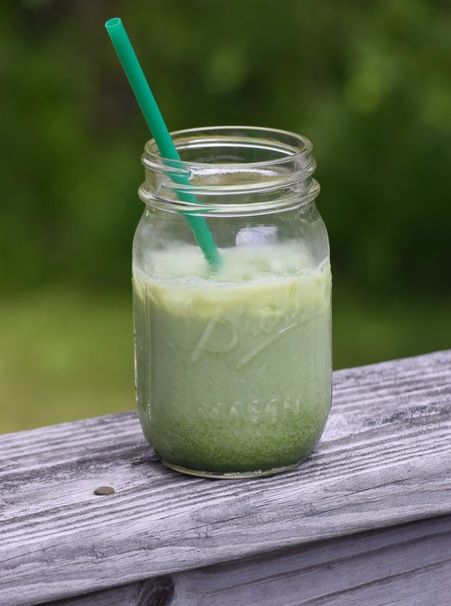 a mason jar filled with green liquid on top of a wooden table