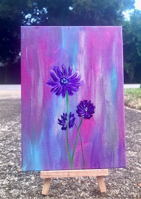 an easel with purple flowers painted on it