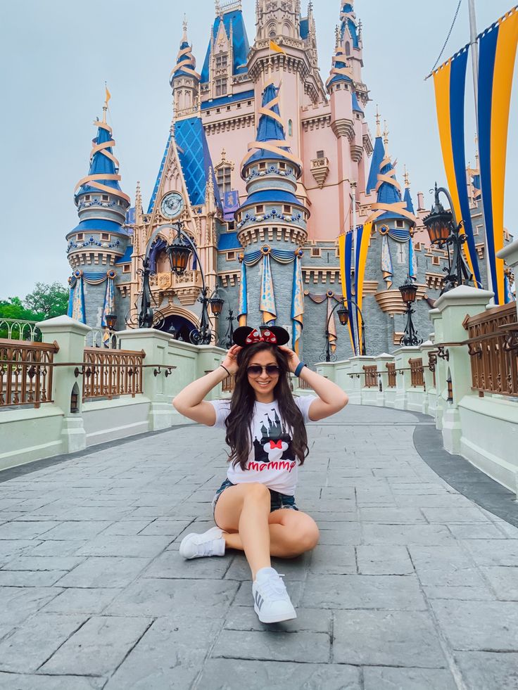 a woman sitting on the ground in front of a castle with her hands behind her head