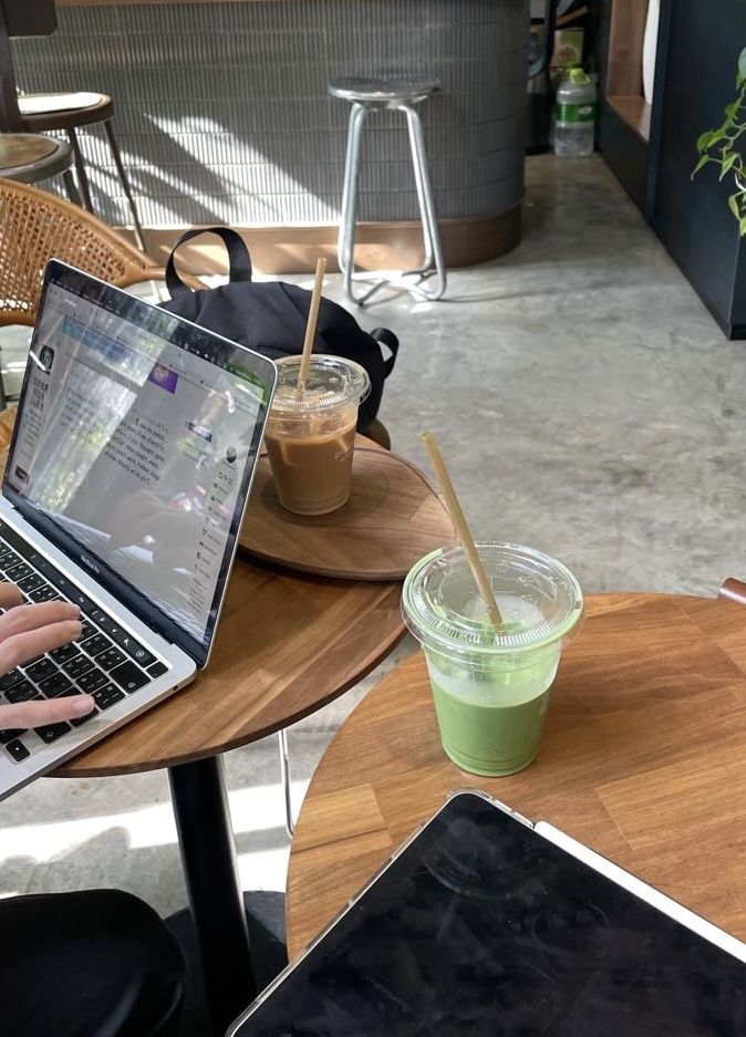 a person sitting at a table with a laptop computer on their lap and a drink in front of them