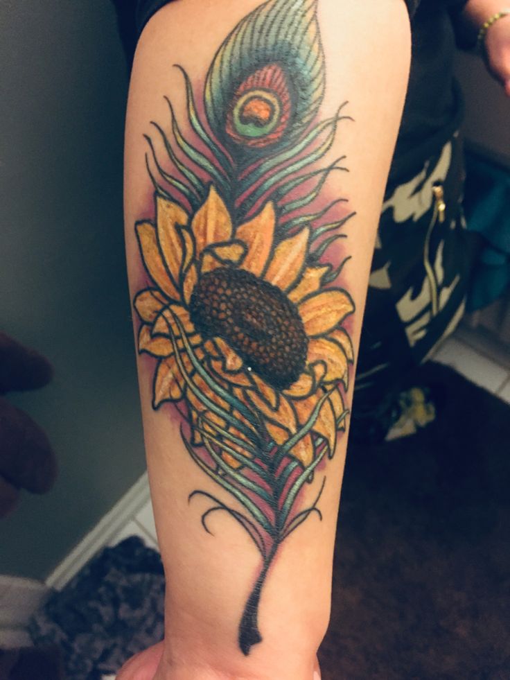 a woman's arm with a tattoo on it that has a sunflower and a feather