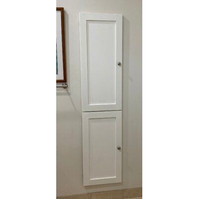 a tall white cabinet in the corner of a room