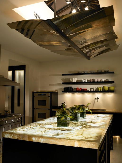 a kitchen with an island counter and lights above the stove top in front of it