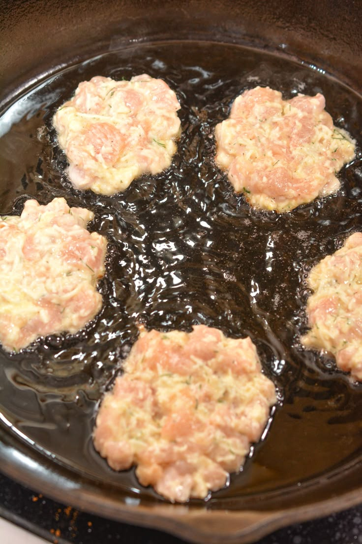 four hamburger patties are cooking in a skillet