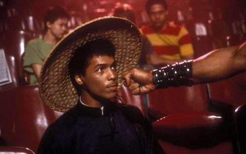 a man with a straw hat on his head in a movie theater, pointing at the camera