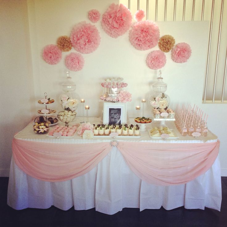 a table topped with lots of pink and white desserts covered in pom - poms