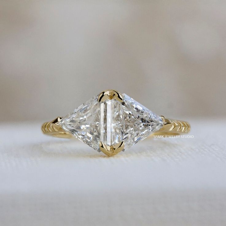 an engagement ring with a princess cut diamond in the center, on a white surface