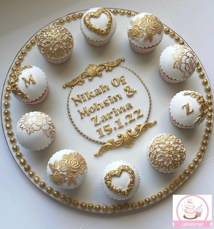 a white and gold wedding cake decorated with cupcakes