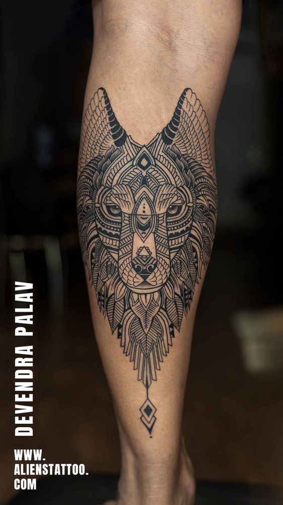 a tattoo on the leg of a person with an animal head and geometric designs in black ink