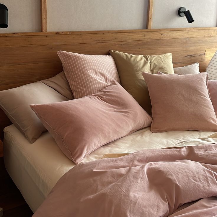 an unmade bed with pink sheets and pillows