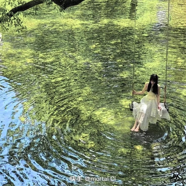 a woman sitting in the water on a swing