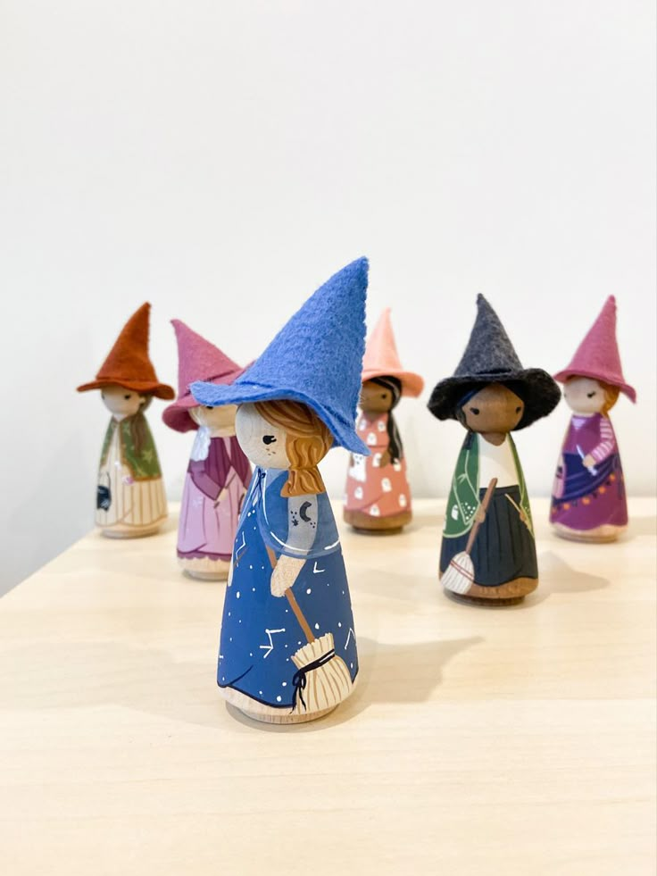 several small wooden figurines with different colored hats on top of a wood table