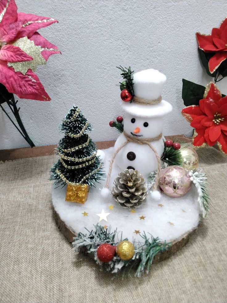 a small snowman sitting on top of a table next to some christmas trees and decorations