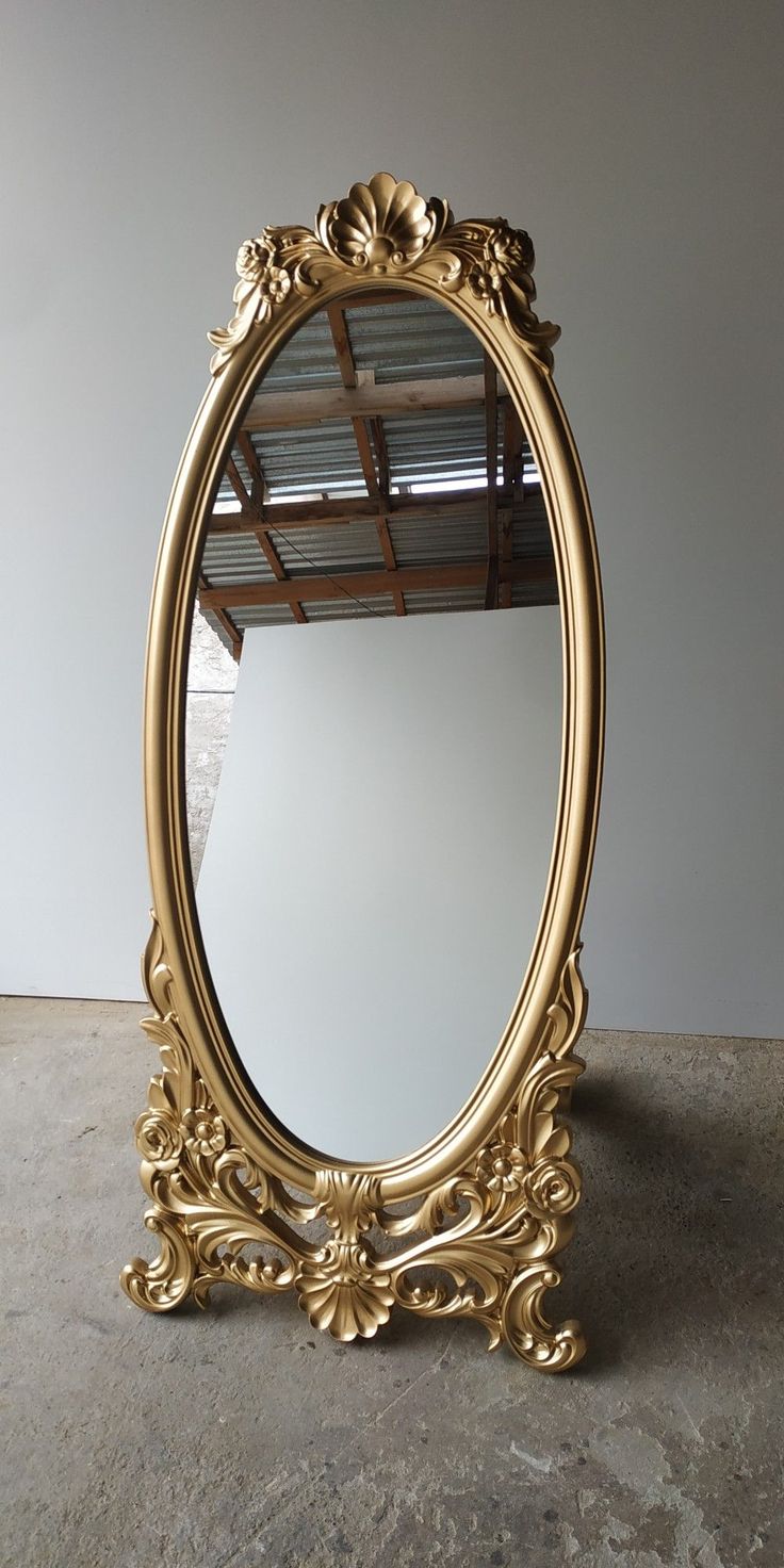 an ornate gold mirror sitting on top of a cement floor