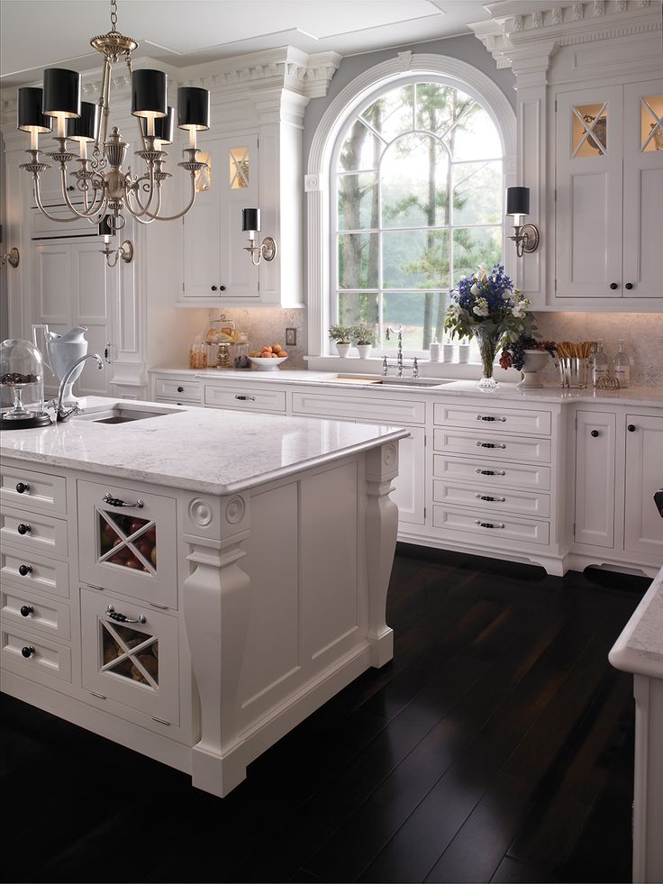 a large white kitchen with an island and chandelier