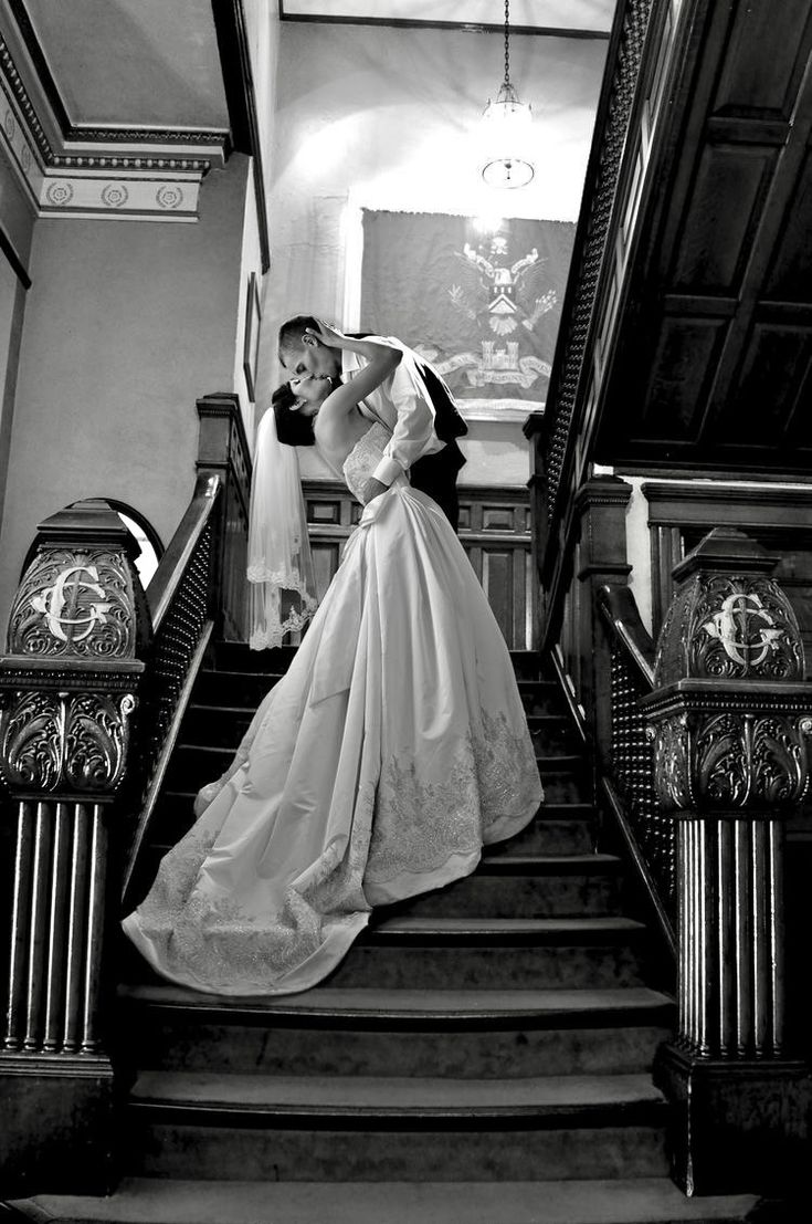 a bride and groom are kissing on the stairs at their wedding reception in black and white