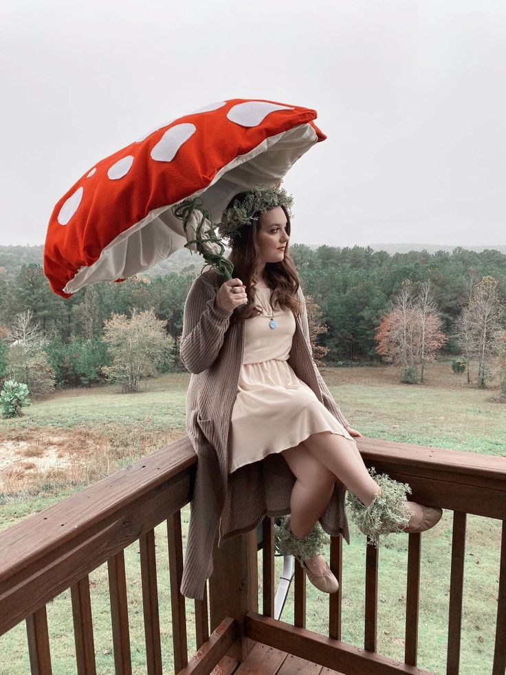 a woman is sitting on a deck with an umbrella over her head and holding flowers