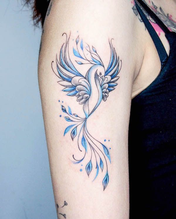 a woman with a blue bird tattoo on her arm and shoulder, showing it's wings