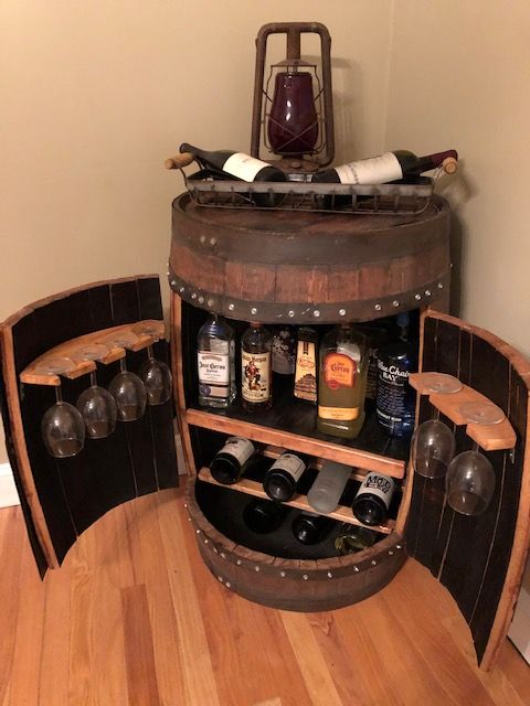 a wooden barrel with wine bottles in it on top of a hard wood floor next to a wall