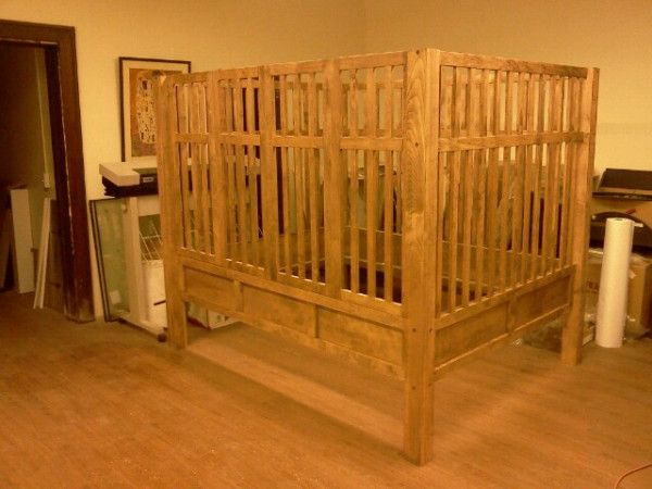 a wooden bed frame sitting on top of a hard wood floor next to a wall