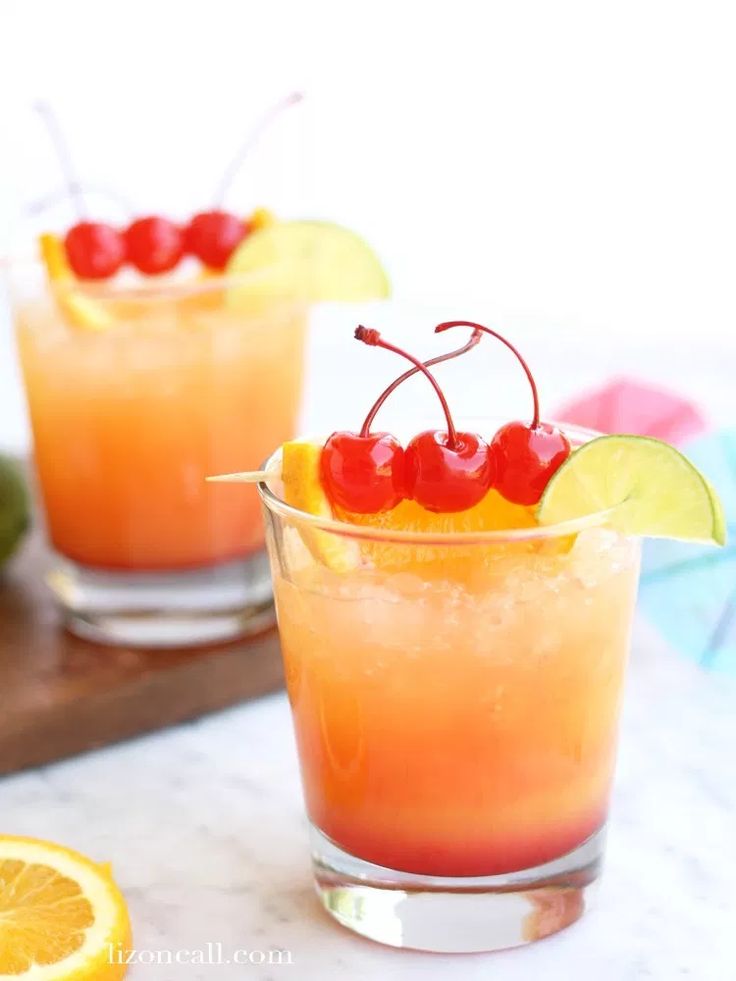 two glasses filled with orange juice and cherries