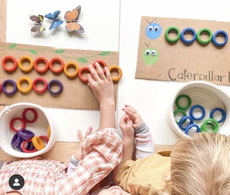 two young children playing with magnets on the wall in front of butterfly themed bulletin boards