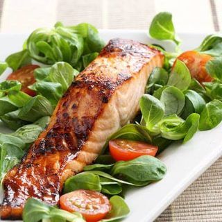 a white plate topped with salmon and greens